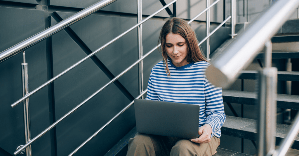 Person sitting on steps working on their laptop