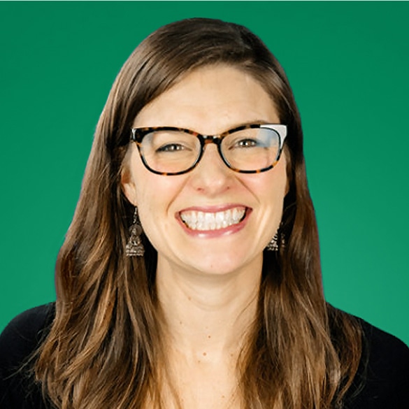 Woman with long brown hair, wearing glasses and earrings, smiles broadly against a solid green background, embodying confidence in the face of HR leadership challenges.